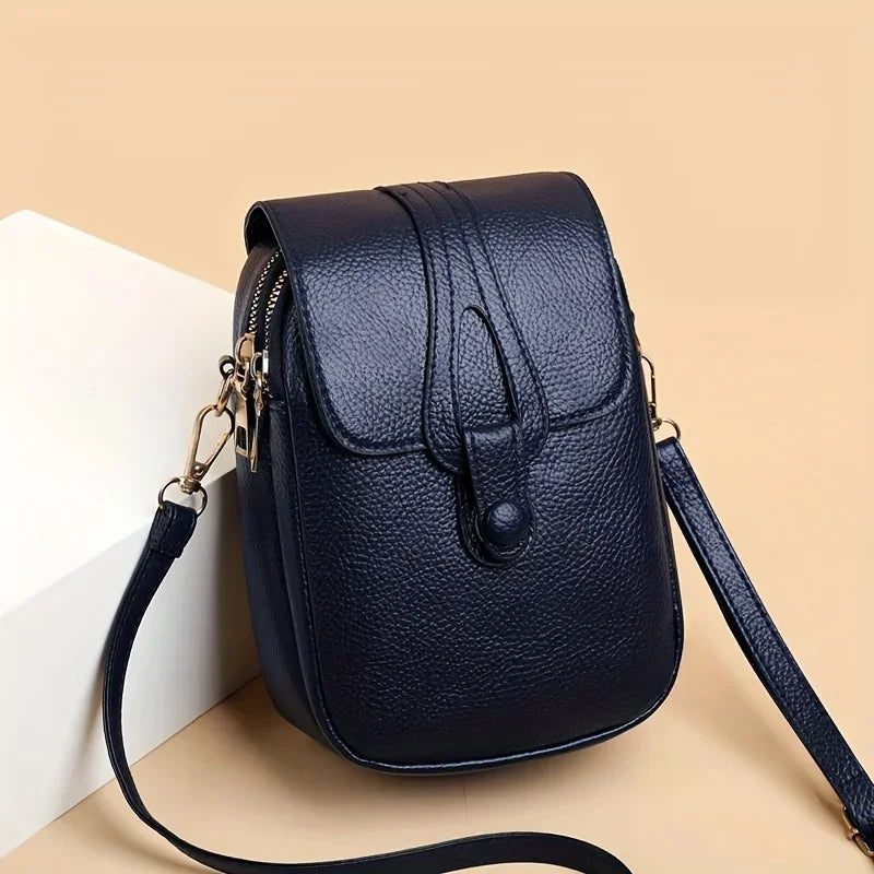 Kompakte Damen-Umhängetasche aus Leder mit minimalistischem Design und verstellbarem Riemen.