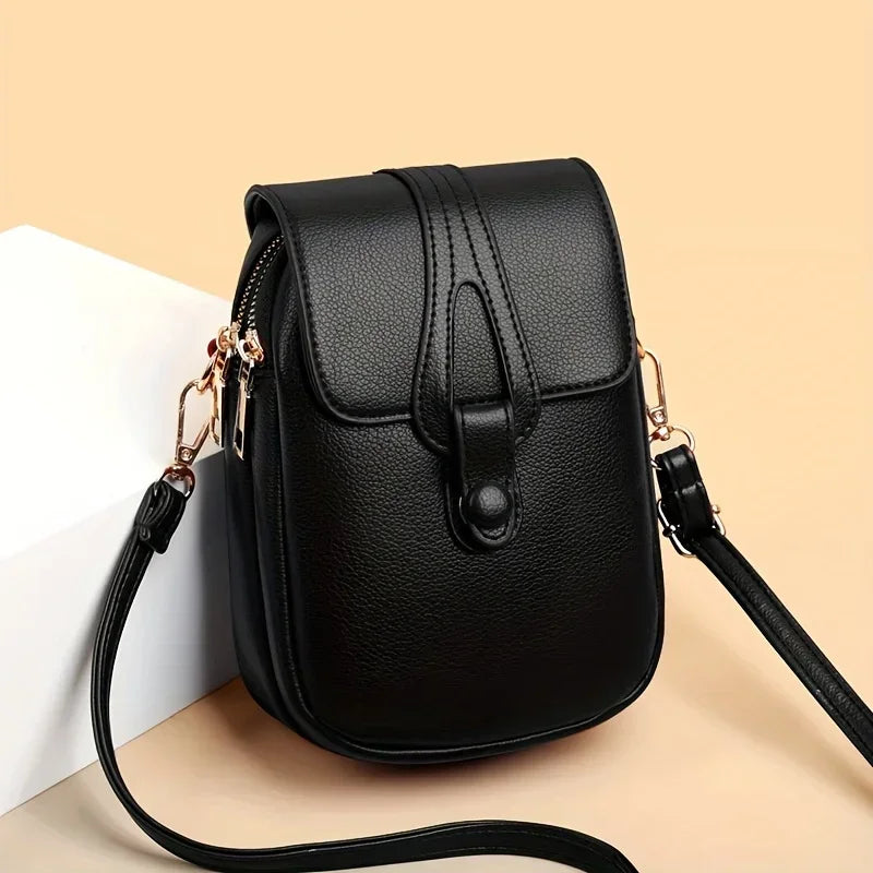 Kompakte Damen-Umhängetasche aus Leder mit minimalistischem Design und verstellbarem Riemen.